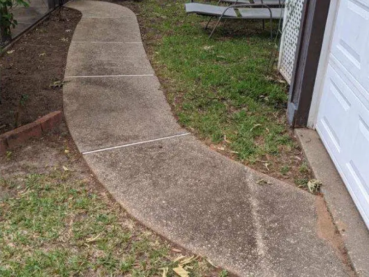 Concrete walkway beside a brick house