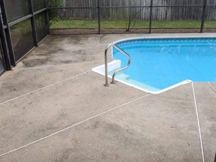 Concrete pool deck beside a screened pool